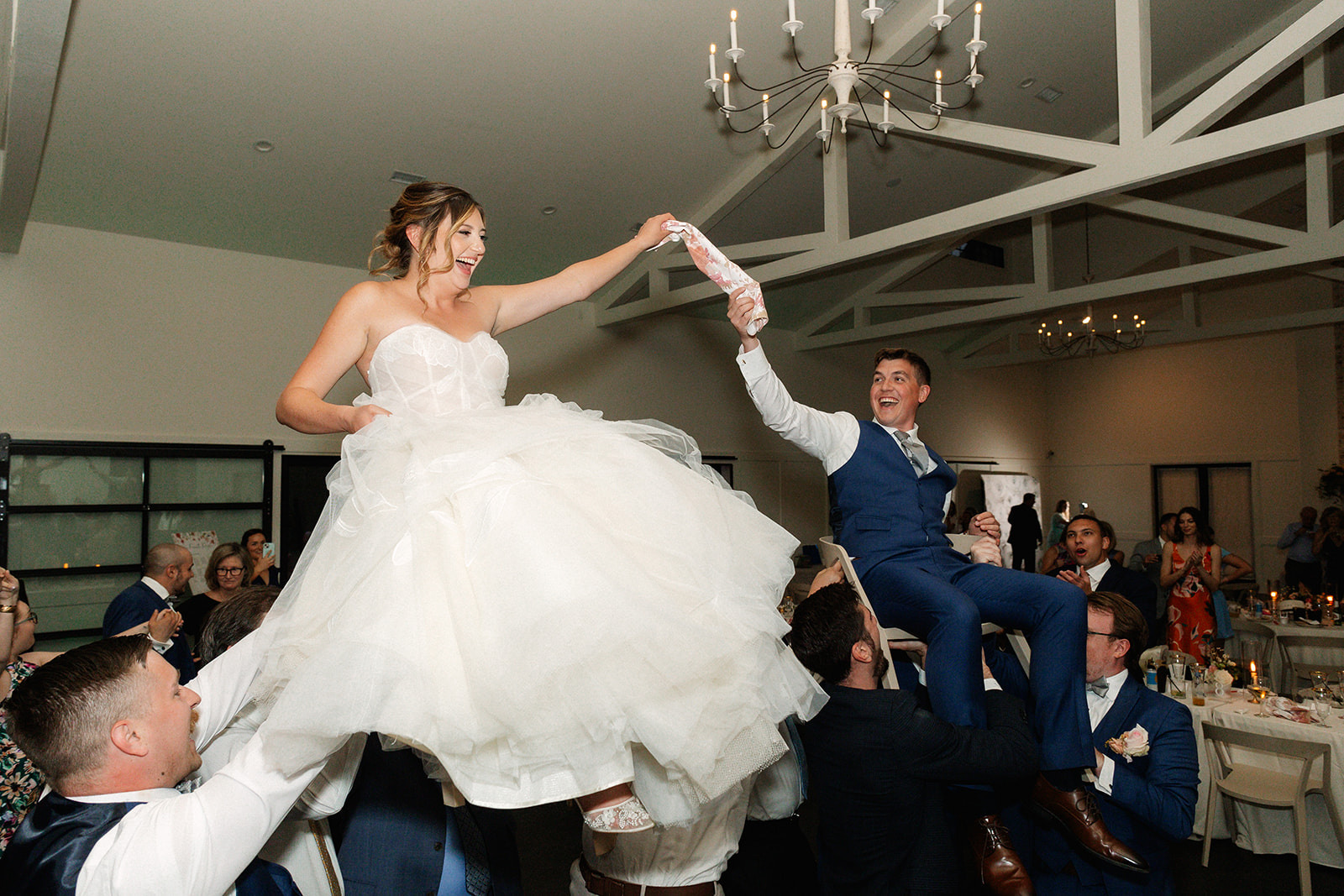 Wedding guests lifting the bride and groom on chairs
